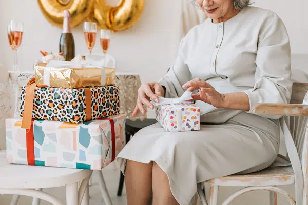 Elderly woman unwrapping birthday gifts