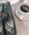 flatlay of chanel bag and black coffee on a marble bistro table